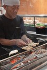 A master yakitori chef grilling skewers over an open charcoal fire, carefully turning each piece with precision.