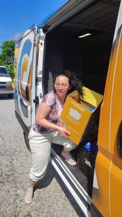 Complete Comfort Heating, Air and Plumbing Call Center Supervisor Christal Galindo unloads a box of some of the 1,200 pounds of food the Indianapolis-based home service company donated to The Refuge’s food bank this month.