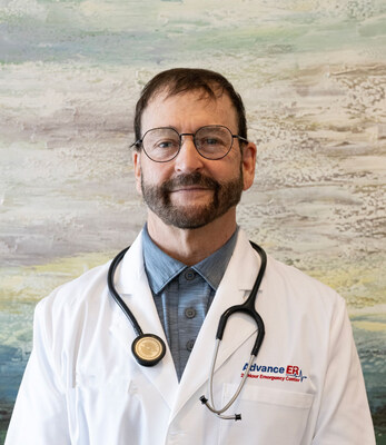 Portrait of Dr. Thomas Allen wearing glasses, a white lab coat with the Advance ER 24 Hour Emergency Center logo, and a stethoscope, standing against a softly textured background.