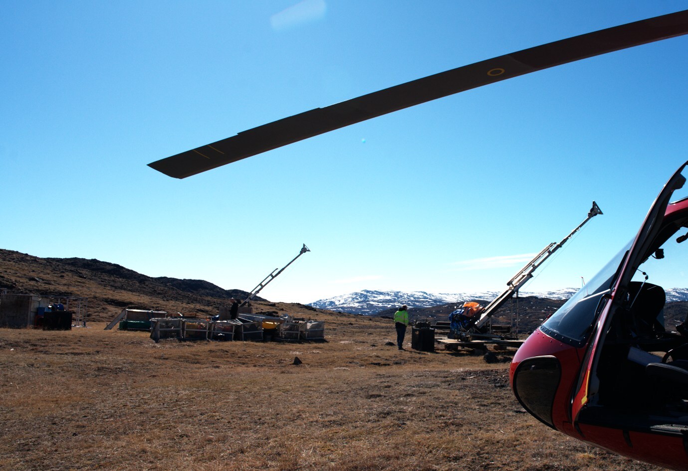 Drill rigs and logistics at Sarfartoq: View across the ST1 plateau showing the  two stored diamond drill rigs, field equipment and the Air Greenland helicopter used during the May 28, 2026 site visit, illustrating the quality of existing drilling and logistics infrastructure at Sarfartoq.