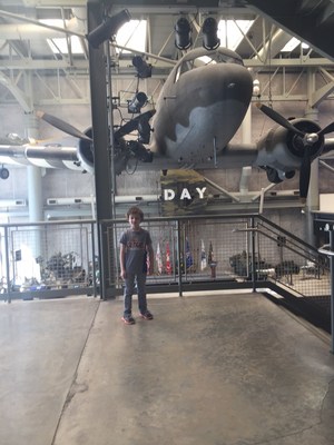 8 year-old Hunter Lee poses in front of a plane in a hanger.
