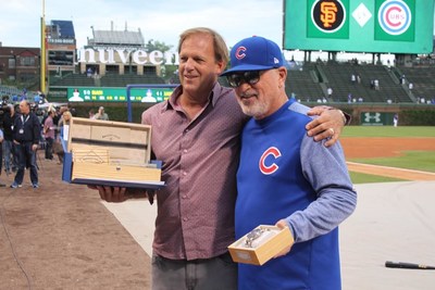 Chicago Cubs Manager Joe Maddon is presented with “The Wrigley Field™ Chrono: Owner’s Edition”, a limited-edition collectors’ Cubs watch featuring wood from original Wrigley Field™ ballpark seats, at a pregame ceremony tonight to celebrate the World Champion’s 1000th victory. [Pictured from left]: Paul Buss, CEO of Original Grain Watch Co.; and Chicago Cubs Manager Joe Maddon.  (Photo courtesy of the Chicago Cubs).