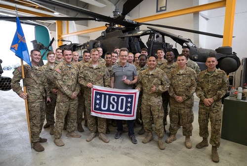 Actor Bryan Cranston (center in grey shirt) poses for a photo with service members in front of a Cobra attack helicopter during a USO tour stop at Katterbach Kaserne in Germany on July 24, 2017. Cranston is visiting servicemen and women as part of a week-long USO tour to Germany and the United Kingdom. USO Photo by Fred Greaves