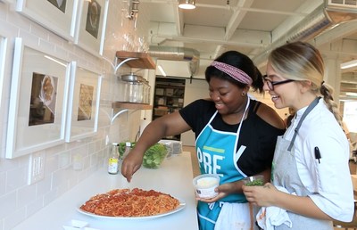 Sarah Russo, Culinary Manager of Chicago-based food startup PRE(r) Brands, guides a Common Threads student through a cooking lesson at PRE's kitchen in Chicago's River North neighborhood.