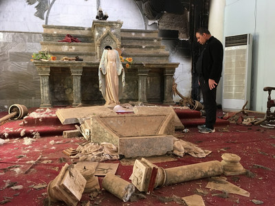 A priest examines the ruins, including a decapitated statue of Mary, in the Catholic church in Karamdes, Iraq, following the town's liberation from ISIS.