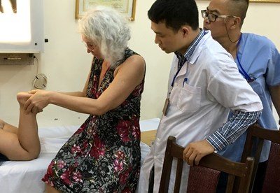 AOFAS volunteer surgeon Isabella V. van Dalen, MD, PhD, examines a patient at the Ba Vi Orthopedics Rehab Center in Ba Vi, Vietnam, as local surgeons observe.