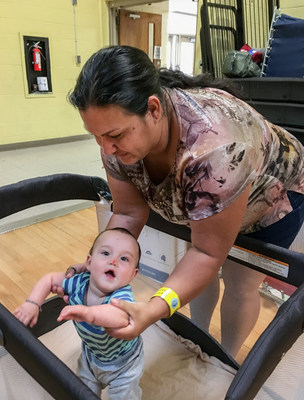 Katrina places her 9-month-old son, Malachi, in a pack-and-play crib. Malachi fell off his cot when he was sleeping and bumped his nose. The family is staying in a hurricane shelter in San Antonio, Texas. Save the Children provided the family with the crib. 