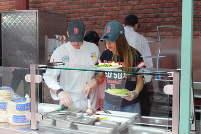 Red Sox fan, Emmy winning host and best-selling author, Maria Menounos, works with Aramark Senior Executive Chef, Ron Abell, behind her new stand at Fenway Park, “Maria’s Greek Kitchen”, which features her family’s recipes and organic ingredients.