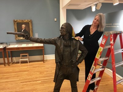California Historical Society executive director Anthea Hartig puts the finishing touches on one of two 400-pound statues on loan from the New-York Historical Society of the famous Hamilton-Burr duel, on display as part of two four-month exhibitions showcasing two versions of the United States' colonial history - British and Spanish - which feature historic and rarely seen artifacts and treasures from the late eighteenth- and early nineteenth-century. Photo Credit:  Kevin Herglotz