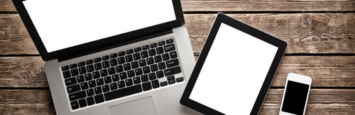 Image of an open laptop, a tablet, and a smartphone on a wooden table.
