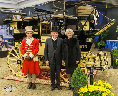 Harvey (center) and Mary (right) Waller with their historic road coach the ‘Old Times,’ winner of the Green Meadows Four-In-Hand Coaching Appointments class at the Royal Horse Show. ﻿Photo by Ben Radvanyi Photography (CNW Group/Royal Agricultural Winter Fair)