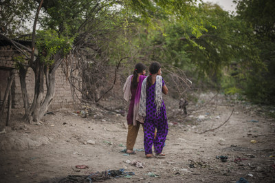 In the evening Kajal, 16, walks with her close friend and cousin Sarita, 17, (pink scarf) to the toilet in an open defacation area, Nihura Basti, Kanpur, India. WaterAid/ Poulomi Basu (CNW Group/WaterAid Canada)