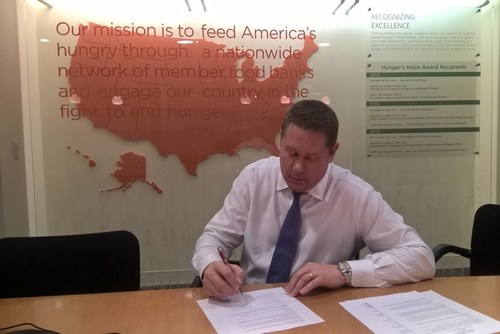 Jay Koster, JLL Group Head, Americas Investor Services, signs an agreement with Feeding America.