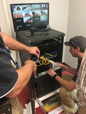 The Holmes Security crew at work: Tommy Page assists technician James Tilley in setting up the Hikvision security hardware at Operation INASMUCH. Here, Tilley kneels to connect camera cables to the NVR.