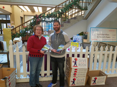 Cory Groshek, author of children's book "Breaking Away: Book One of the Rabylon Series" and founder of Manifestation Machine, with Meg Deem of the Friends of the Brown County Library, who is accepting copies of "Breaking Away" on behalf of the annual Give a Kid a Book campaign at the Central Library in downtown Green Bay, Wisconsin.