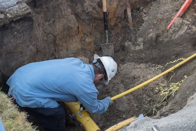 An employee of DTE Energy's Gas Renewal Program team attaches a new service line from a customer's home to a new main pipeline.