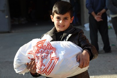 Little boy manages a portion of his family's "Christmas basket," a gift from the Knights of Columbus to persecuted Christians in Iraq.