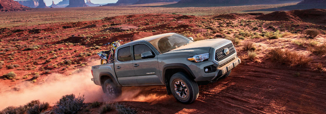 2018 Toyota Tacoma driving off-road through sand dunes.