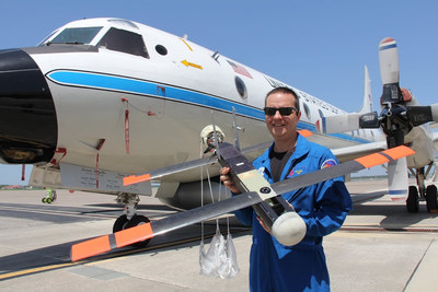 Dr. Joseph Cione, hurricane researcher at NOAA's Atlantic Oceanographic and Meteorological Laboratory and principal investigator of NOAA’s Coyote project, holds the UAV in front of NOAA’s P-3 aircraft at MacDill Air Force Base in Tampa, Florida. (Photo: National Oceanic and Atmospheric Administration)