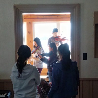 Campers practice the violin at Dixon Hall Music School's March Break camp at Hart House Farm in 2017. This year's camp program includes a special learning component around the Syrian refugee crisis, and connects campers with Syrian refugees living in Jordan who also study music. (CNW Group/Dixon Hall Neighbourhood Services)