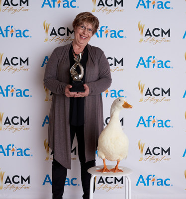Aflac ACM Lifting Lives Honoree Judith Pinkerton poses with the Aflac Duck and her trophy.