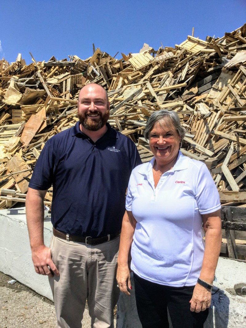 Environmental superheroes Lynda Hogue and Lincoln Young check out the towering pile of discarded wood that will become fuel for the gasification plant.