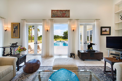 Shown here, the relaxing salon offers views and walkout access to the property’s pool and spa. The 50-ft saltwater pool is surrounded by coral stone. Learn more at WellingtonLuxuryAuction.com.