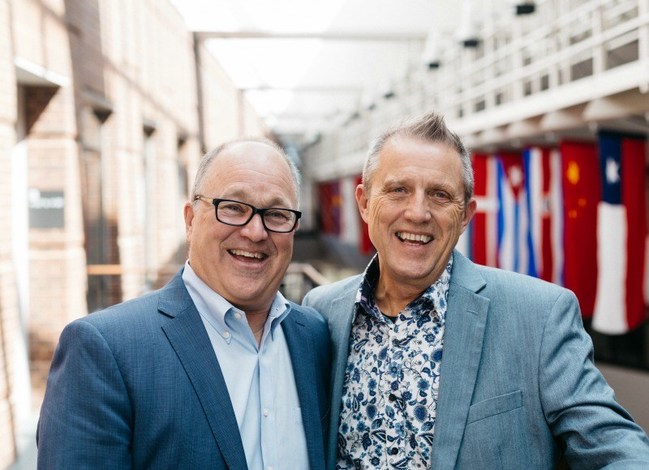 Charlie Rounds and Don Ofstedal in front of flags