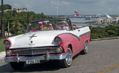 A Cuban taxi driver, piloting a vintage car, pulls up to the El Morro Castle while the Carnival Paradise cruise ship is docked in Havana, Cuba. (Andy Newman/Carnival Cruise Line)