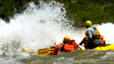 A commercial raft from a member of the Arkansas River Outfitters Association (AROA) drops a rapid at high water on the Arkansas River in Colorado.