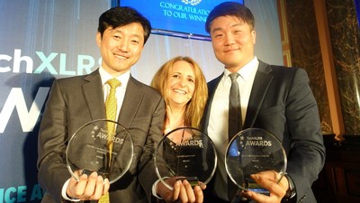 Jeong Jun-Ho, left, a team manager of KT’s Mobile Access Network Technology Department, and Song Min-Kwan, right, a manager of KT’s Market Strategy Business Unit, pose with an emcee during an award ceremony of TechXLR8 at Gibson Hall in London on June 12. (PRNewsfoto/KT Corp.)