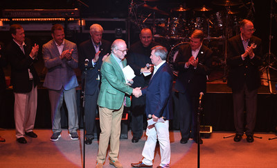 National Football Foundation board chair and hall of famer, Archie Manning, extends a congratulatory handshake to Ben Sutton during his induction ceremony into the National Football Foundation Leadership Hall of Fame.  Looking on in support are fellow Commissioners, Athletic Directors and industry VIP's.