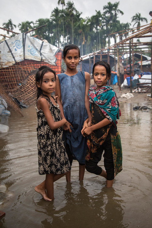 Three girls, all Rohingya refugees, are photographed in the flooded part of the camp where they live in Shamlapur, Cox's Bazar District, Bangladesh (June 2018). © UNICEF/UN0217536/LeMoyne (CNW Group/UNICEF Canada)