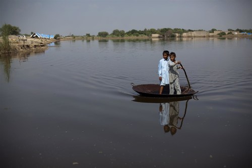 September 2011: Boys use a large steel pot as a raft to cross an expanse of flood water in Nihalbaladi Village, in Khairpur District, Sindh Province, Pakistan. © UNICEF/UNI116709/Zaidi (CNW Group/UNICEF Canada)