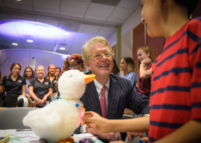 Aflac Chairman and CEO Dan Amos huddles with 8 year old cancer patient Alexander Montes with the My Special Aflac Duck at an event held at Palmetto Health Children's Hospital in Columbia, South Carolina