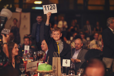 Pictured is Aiden, brother of St. Jude patient Connor who passed away from cancer. When he stood and raised his auction paddle at the St. Jude Fall Festival of Hope, he inspired the entire room to stand and break fundraising records in Connor's memory.