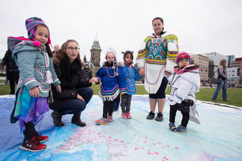 Des élèves du Centre des enfants inuits d’Ottawa explorent la carte-tapis géante de l’Atlas des peuples autochtones du Canada au lancement des ressources éducatives sur la Colline du Parlement à Ottawa. (Groupe CNW/Société géographique royale du Canada)