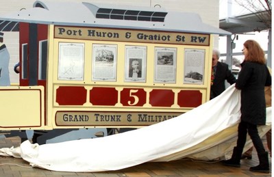 TRANSIT HISTORY UNVEILED: Blue Water Area Transit General Manager Jim Wilson and artist Mino Duffy Kramer unveil a new sculpture that tells the story of transit innovation in Port Huron, Michigan, starting some 150 years ago with William Pitt Edison’s horse-pulled trolley service. (photo by Rose Norton)