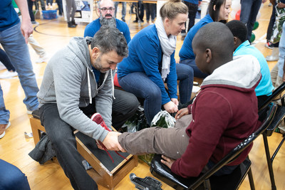 Genesco’s Mario Gallione (president of its Journeys division) helps fit students at Nashville’s Park Avenue Elementary with new shoes. On Friday, Dec. 14, 200 employees from Genesco set up a mock shoe store and fitted app. 400 students with new shoes and a warm hat for the holidays as part of its 29th annual “Cold Feet, Warm Shoes” community outreach event. Photo credit: Gregory Byerline