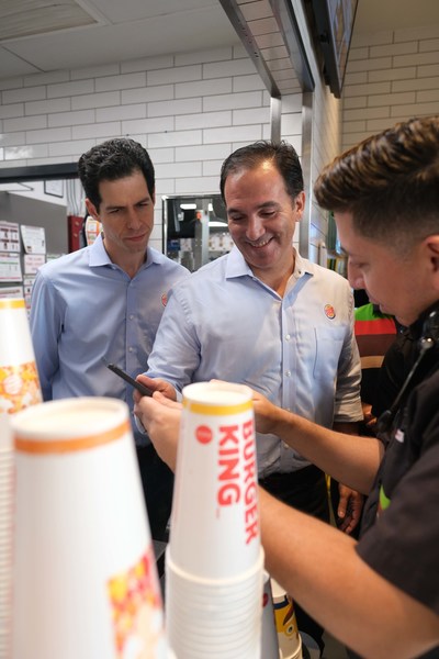 (L to R): Daniel Schwartz (Executive Chairman of RBI and co-Chairman of RBI’s Board of Directors) and Jose Cil (CEO of RBI) meet with a Team Member at a Burger King restaurant in South Beach, Miami. (CNW Group/Restaurant Brands International Inc.)