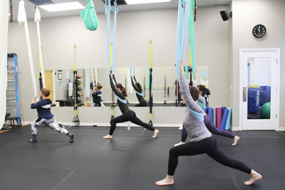 Yoga Lily students learning beginner-level aerial yoga techniques.