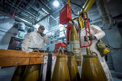 An ordnance technician uses a lift assist to place a simulated munition onto a conveyor as a part of systemization activities. The systemization phase is nearing completion at the Pueblo Chemical Agent-Destruction Pilot Plant.