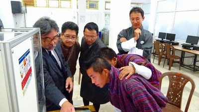 Junichi Kurata (far left) describing the components of the 3D printer to JNEC students and teachers.