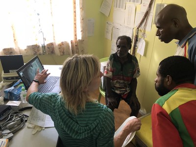 Dr. Carolyn Marquardt consulting with a patient and advising Community Health Workers regarding patient's x-ray image in Sapmanga village, YUS
