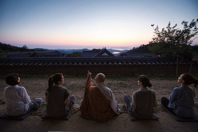 A monk and Templestay participants watching the sunset in Mihwangsa Temple