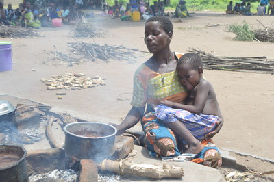 Eneless Bernard prepares a meal at Chagambatuka Primary School camp in Chikwawa as her 3-year-old daughter Lincy cries in her mother's arms  UNICEF Malawi/2019/ Rebecca Phwitiko (CNW Group/UNICEF Canada)