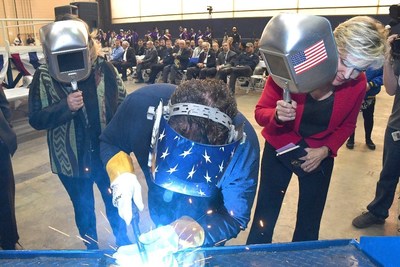 A welder authenticates the keel of LCS 25, the future USS Marinette, by welding the initials of ship sponsor Jennifer Granholm.