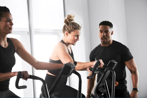 A personal trainer encourages two people during a Life Time group fitness class 