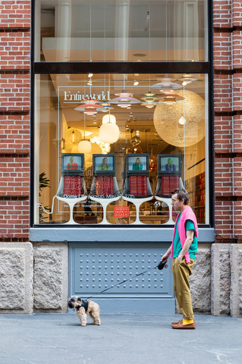 Entireworld Founder and Creative Director Scott Sternberg stands with his dog General Zod in front of the Dome Life pop-up at DWR's SoHo Studio. In the windows, original video created by Entireworld brings the concept to life – models wearing Entireworld interact with furniture and objects from Design Within Reach. Photo: Alexander Kusak