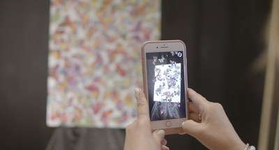 A Park West Gallery art collector views artist Tim Yanke's new augmented reality-enhanced "Reveal" art through their smartphone.
